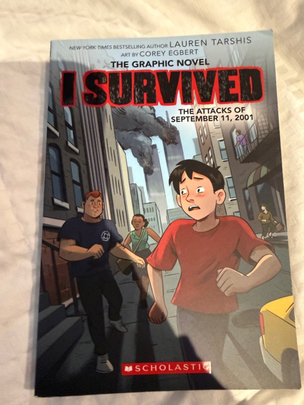 Scholastic Graphic Novel with Bright Red Title and Muted Gray-Blue Cityscape